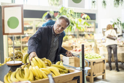 Mature man buying bananas in organic supermarket