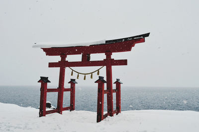 Lifeguard hut on sea shore during winter against sky