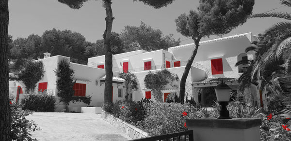 Snow covered houses and trees by buildings against sky