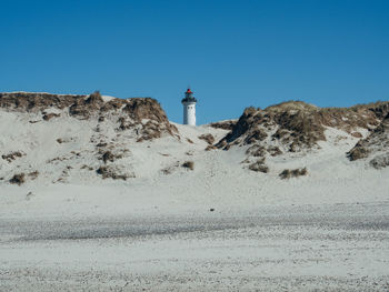 Lighthouse on street amidst buildings against clear sky