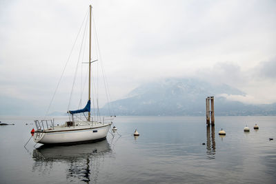 Sailboats moored in sea against sky