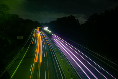 Light trails on highway in city against sky at night