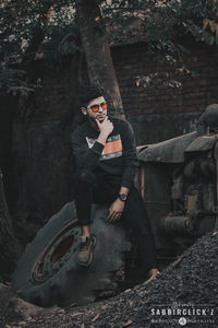 Portrait of young man sitting on tree