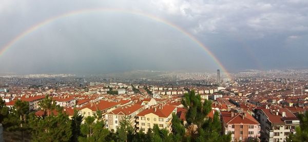Aerial view of rainbow over buildings in city against sky