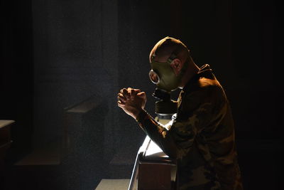 Man wearing gas mask while standing in darkroom