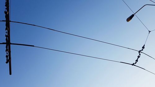 Low angle view of electricity pylon against clear blue sky