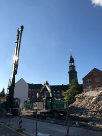 Tower amidst buildings in city against clear blue sky