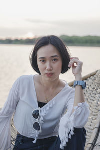 Portrait of beautiful young woman standing against sea