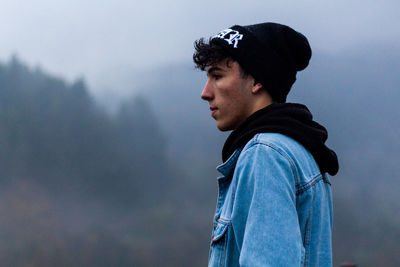 Side view of young man looking away outdoors