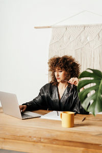 Young woman using mobile phone while sitting on table