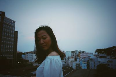 Young woman in city against clear sky