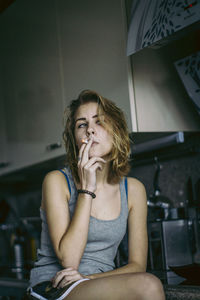 Young woman smoking cigarette at home