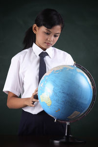 Schoolgirl with globe against blackboard