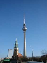 Communications tower in city against blue sky