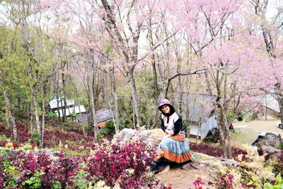 Woman sitting on pink cherry blossom