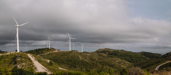 Panoramic view of windmills in mountains against cloudy sky