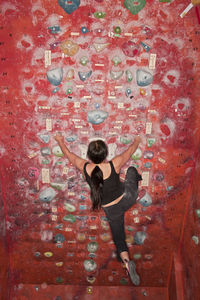 Full length rear view of woman standing against red wall