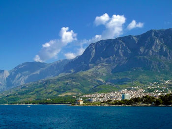 Scenic view of sea by townscape against sky