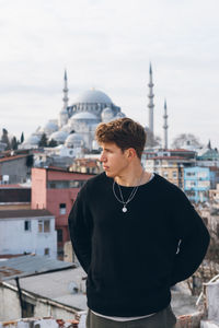 Young man standing on buildings in city