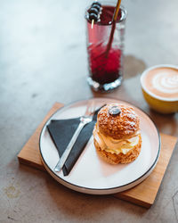 Cropped of the purple cocktail in glass, cake dessert and cappuccino standing on the table