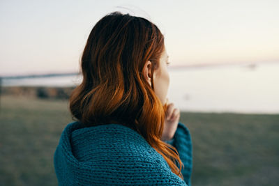 Beautiful woman standing at beach against sky during sunset