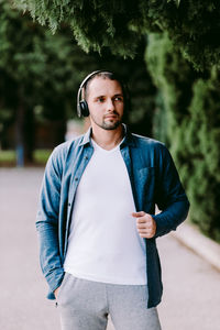 Portrait of young man standing against trees