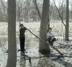 Full length of woman standing on tree trunk in forest