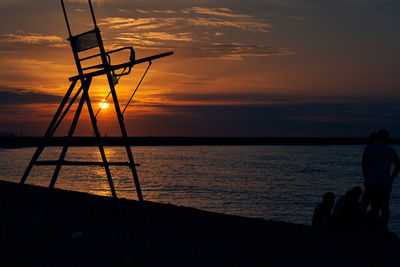 Silhouette people on beach against sky during sunset