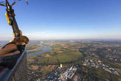 Mid adult woman traveling in hot air balloon over cityscape