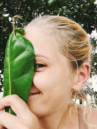 Close-up portrait of woman holding leaf
