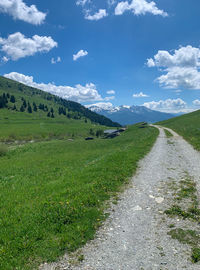 Road amidst field against sky