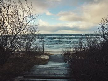 Pier on sea against cloudy sky