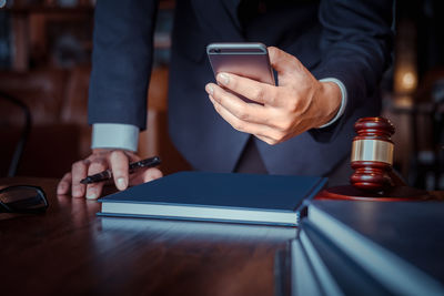 Midsection of man using mobile phone on table