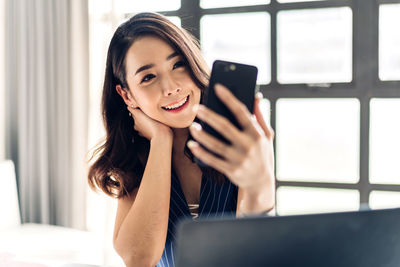 Portrait of smiling young woman using mobile phone