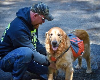 Side view of man with golden retriever on street