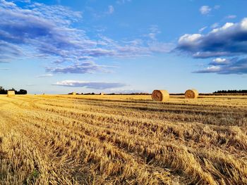 Hay bales on field against sky