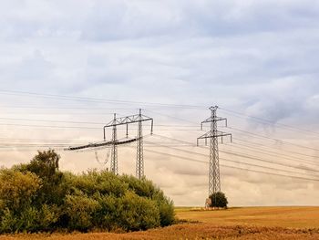 Electricity pylon on field against sky