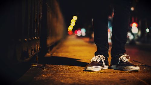 Low section of man standing on road at night