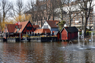 Houses by river against buildings