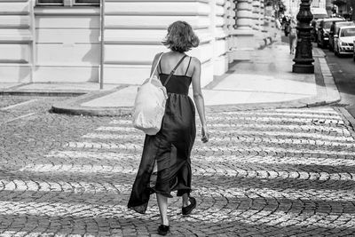 Rear view of woman crossing road in city