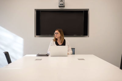 Young woman using phone while sitting on table