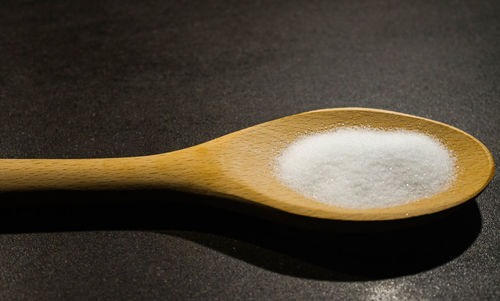 Close-up of sugar in wooden spoon on table