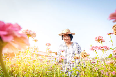 Low angle view of person on flowering plants against clear sky