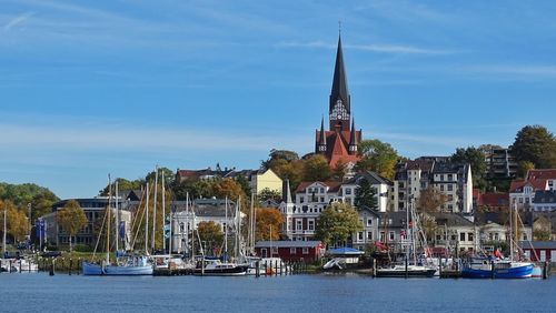 Sailboats in building by city against sky