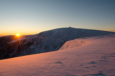 Scenic view of snowcapped mountains against clear sky during sunset