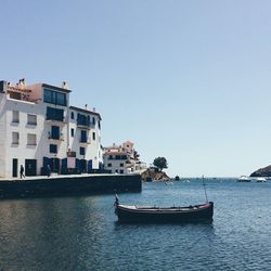 Boats in calm sea against clear sky