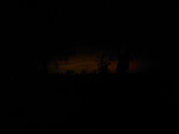 Defocused image of silhouette landscape against sky at night