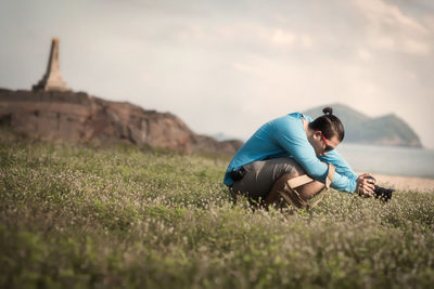 Side view of boy sitting on field