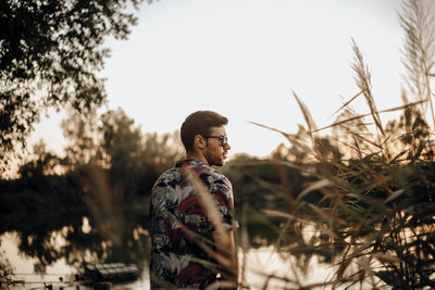 Young man with sunglasses on his back on a lake at sunset