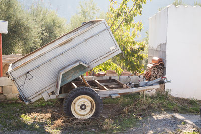 Abandoned vehicle trailer on field against trees